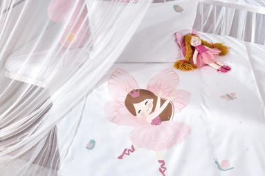 Weißes Babybett mit rosaweißer Bettwäsche