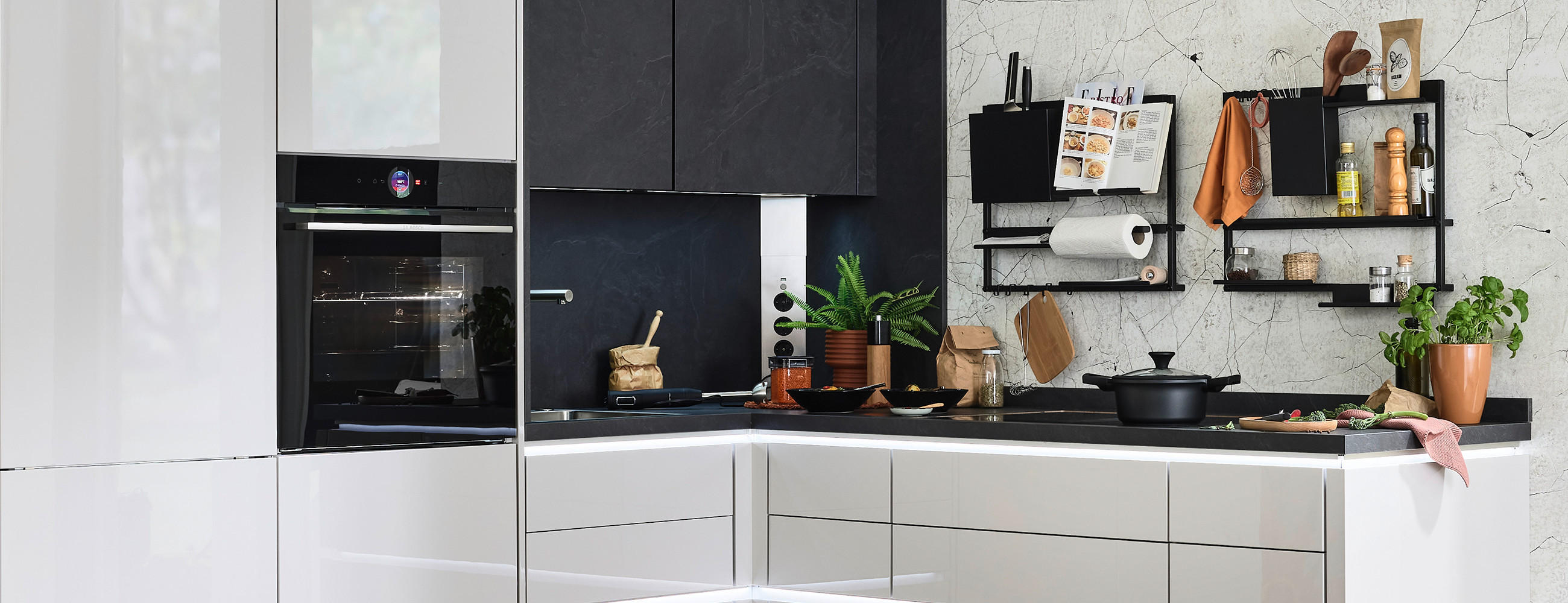 Glänzende Küche in Black and White Optik und mit reichlich Küchenutensilien auf Arbeitsplatte und in den Regalen.