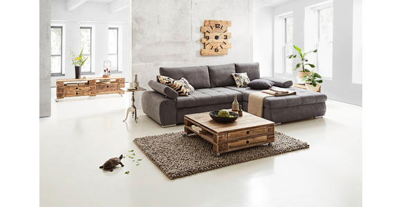 Das Bild zeigt ein Wohnzimmer mit einer grauen Couch, einem Couchtisch aus Paletten, einem Teppich, einem Sideboard aus Paletten, einem Kerzenhalter, einer Uhr, zwei Fenstern, einer Pflanze und einer Schildkröte.