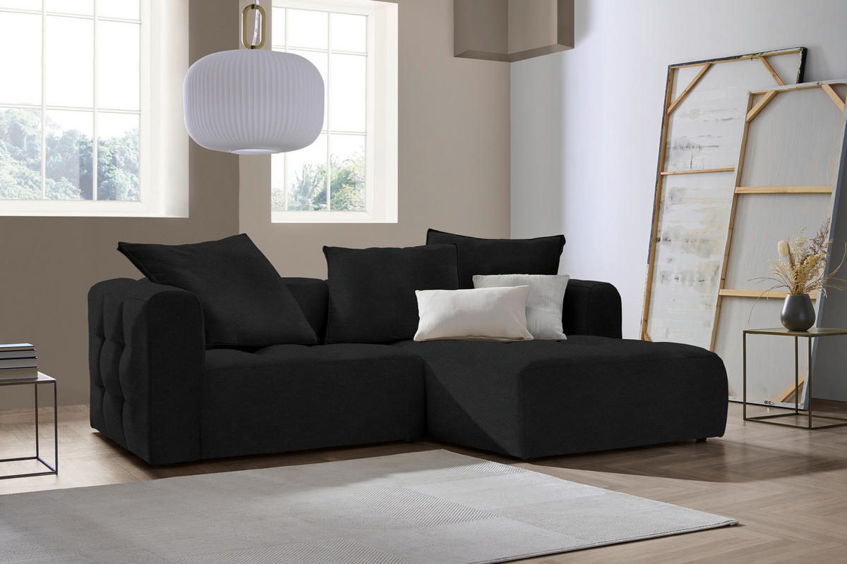 Stylife ECKSOFA MOSSO Schwarz Webstoff, links davon: Hochflorteppich in weiß, Sofa, Deckenbeleuchtung, rechts davon: Beistelltisch in hellem Wohnzimmer.