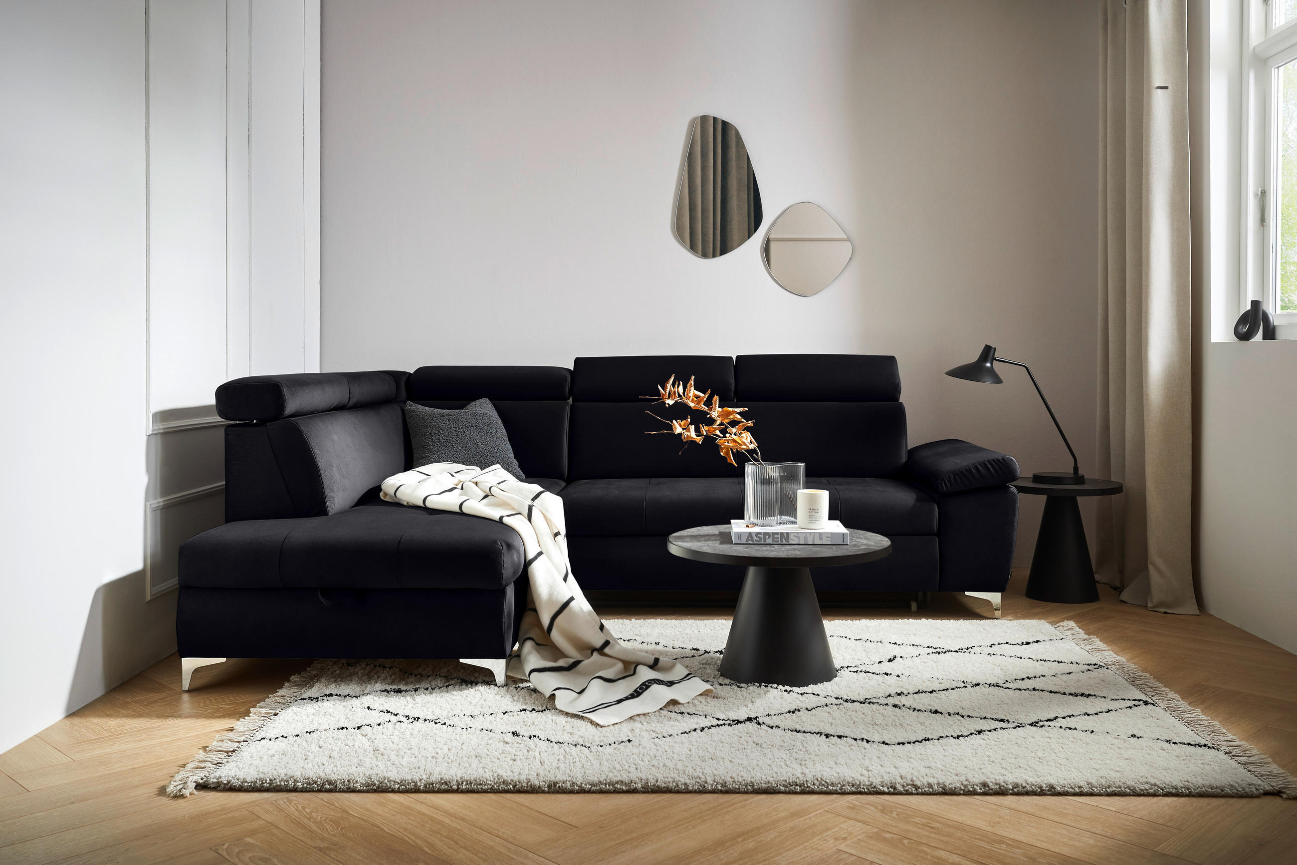 Carryhome ECKSOFA Schwarz Mikrofaser, links davon: Decke in schwarz, rechts davon: Hochflorteppich in weiß, Beistelltisch, Tischleuchte in schwarz in hellem Wohnzimmer.