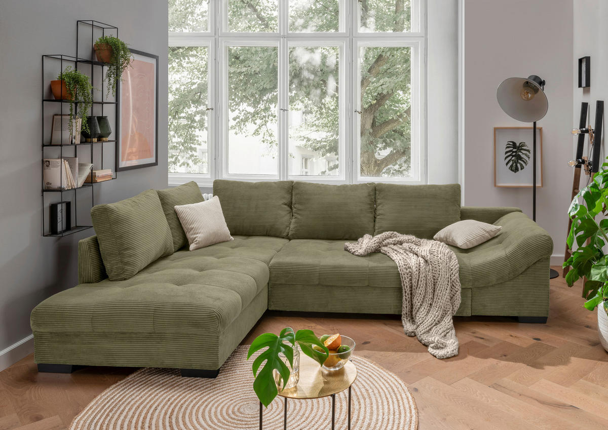 MID.YOU ECKSOFA Olivgrün Cord, links davon: Regal, Kissen in grün, rechts davon: Decke, Topfpflanze in grün in hellem Wohnzimmer.