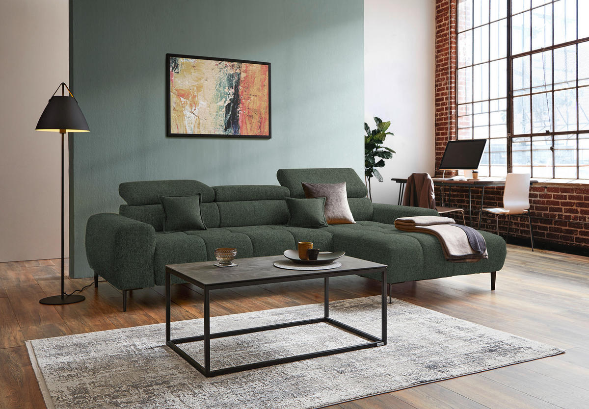 Welnova ECKSOFA Dunkelgrün Webstoff, links davon: Hochflorteppich in grau, Bild, rechts davon: Couchtisch, Decke in hellem Wohnzimmer.