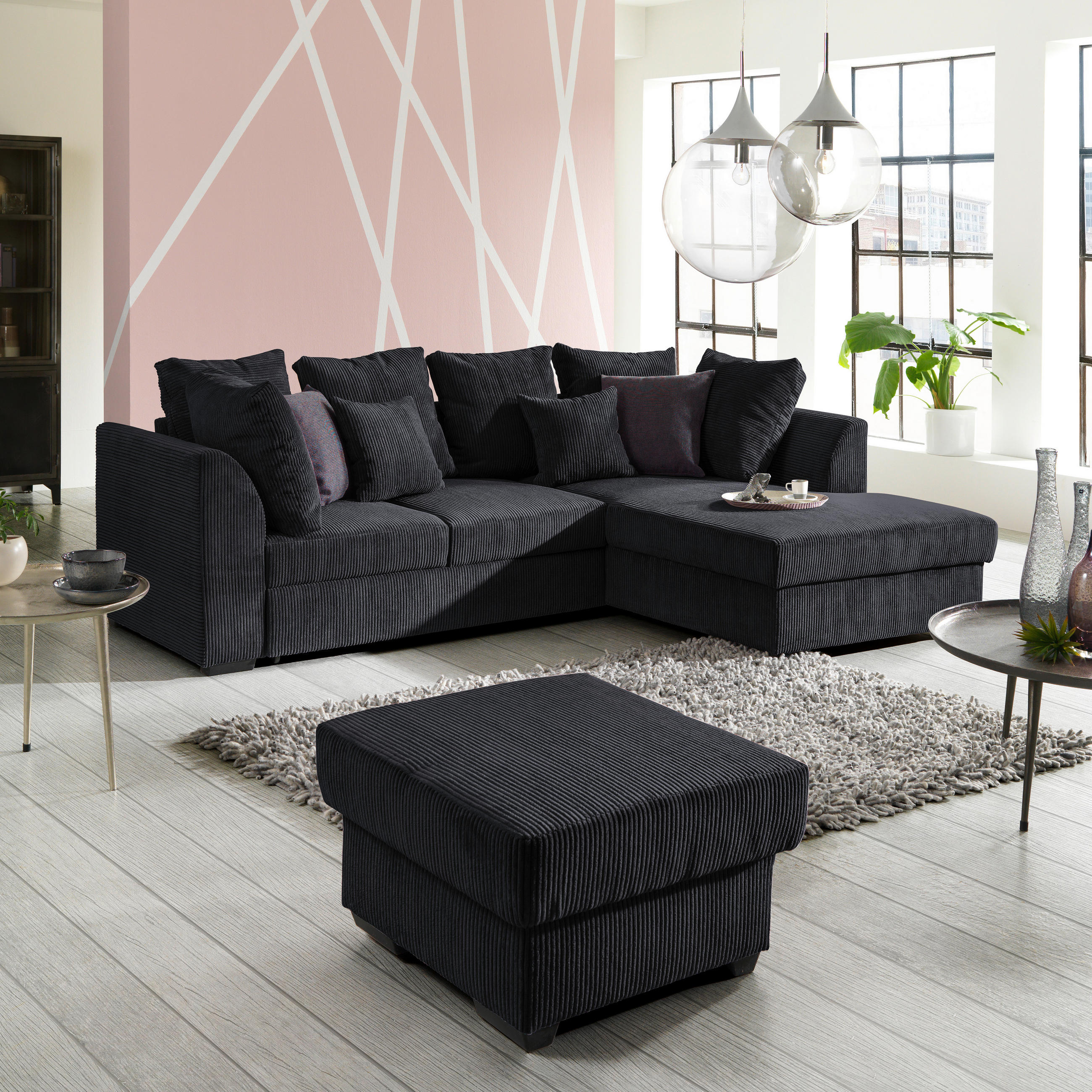 Cantus ECKSOFA inkl.Funktionen Schwarz Cord, links davon: Beistelltisch, rechts davon: Hochflorteppich in grau, Topfpflanze in grün, Kissen in hellem Wohnzimmer.