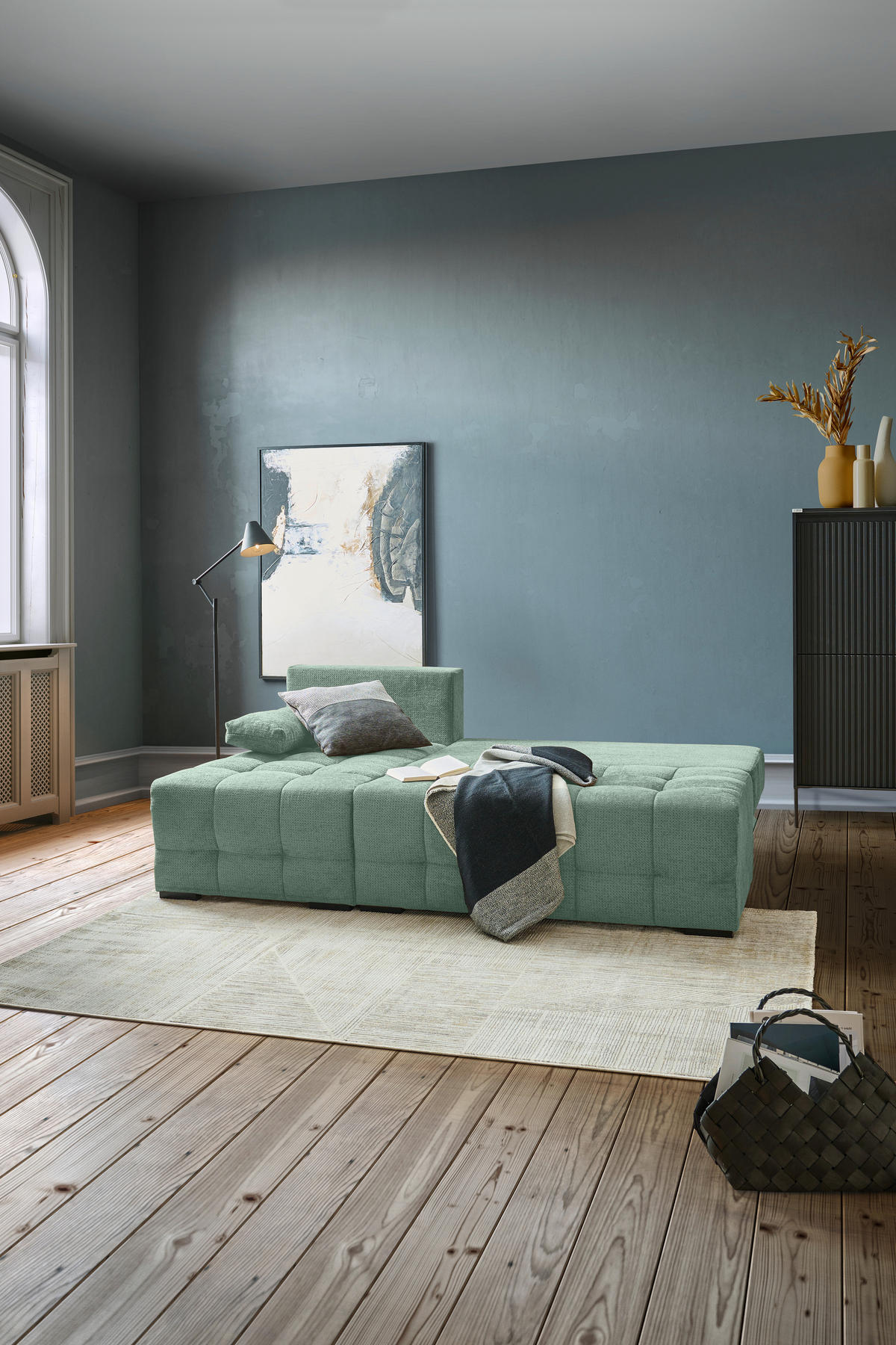 home24 ECKSOFA Dunkelgrün Chenille, links davon: Hochflorteppich in grün, Bild, rechts davon: Vase in hellem Wohnzimmer.