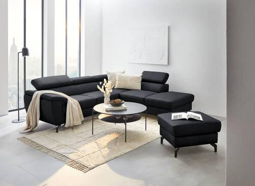 Celina Home ECKSOFA Schwarz Echtleder, links davon: Webteppich, rechts davon: Hocker in schwarz, Couchtisch in schwarz, Lektüre in heller Toilette.