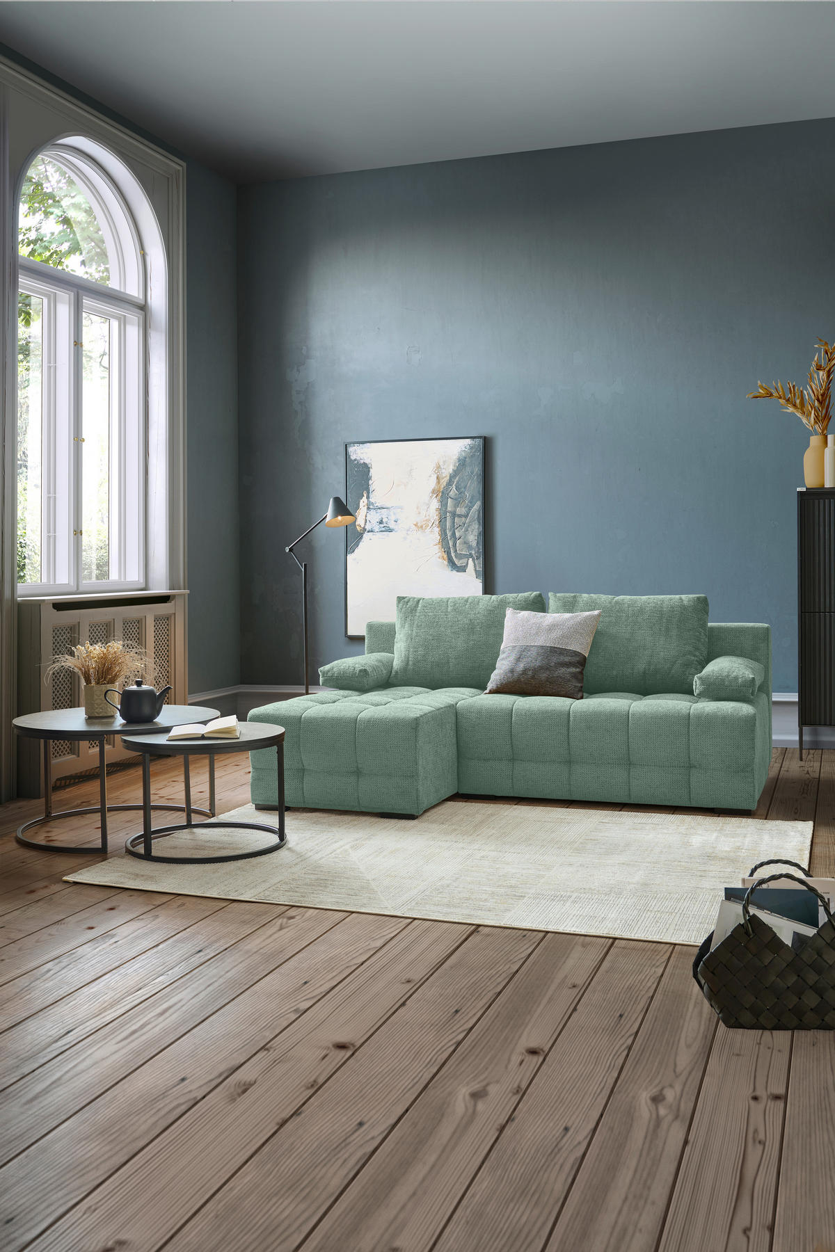 home24 ECKSOFA Dunkelgrün Chenille, links davon: Hochflorteppich in grün, Couchtisch, rechts davon: Bild in hellem Wohnzimmer.