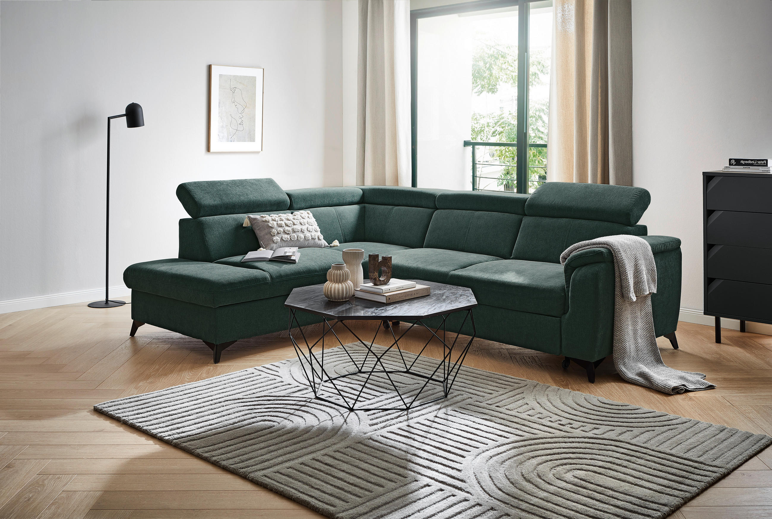 Stylife Ecksofa inkl. Funktionen PRAG Petrol, Dunkelgrün Chenille, rechts davon: Webteppich in grün, Couchtisch, Decke in grün, Gardine in hellem Wohnzimmer.