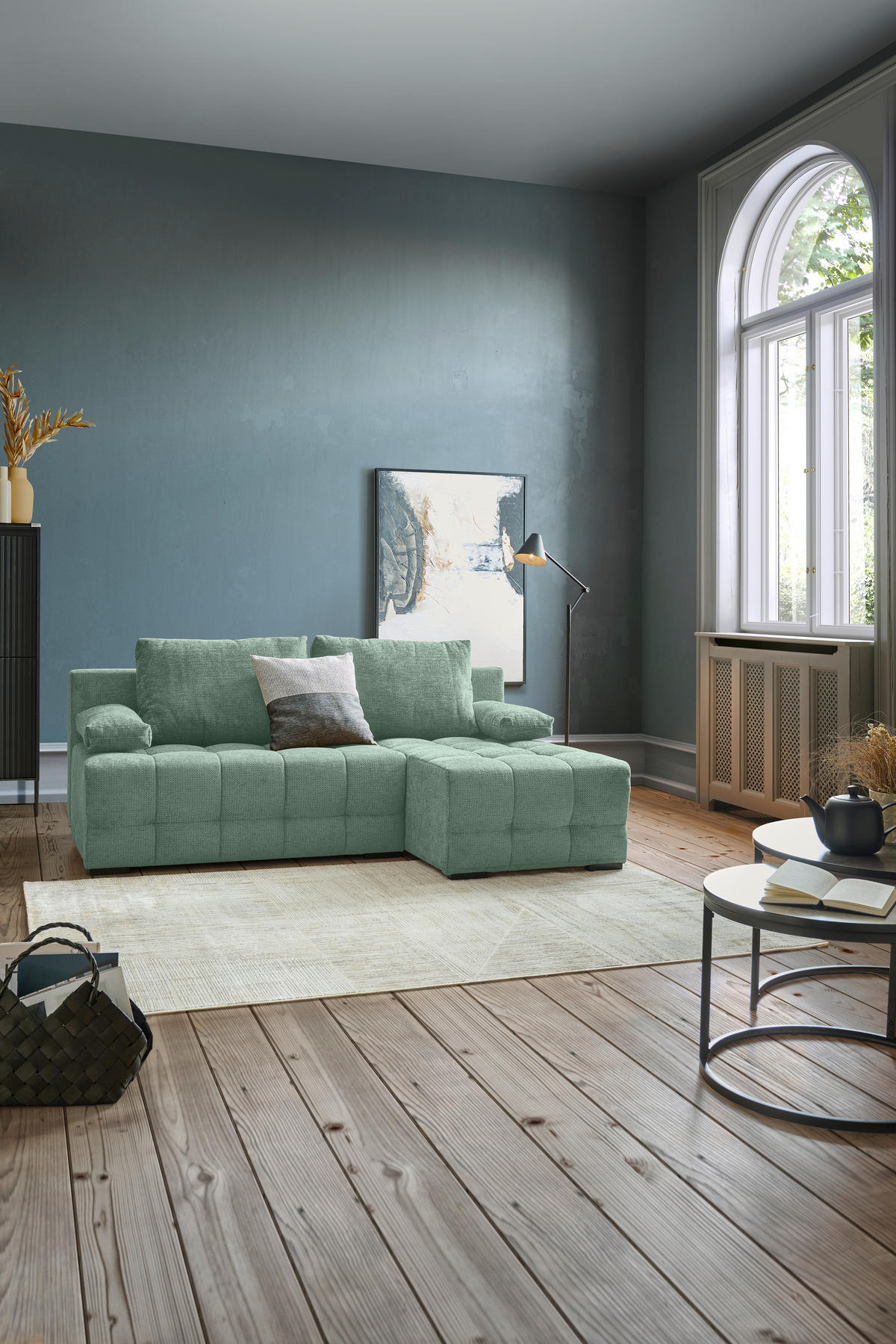 home24 ECKSOFA Dunkelgrün Chenille, rechts davon: Hochflorteppich, Beistelltisch, Highboard, Bild in hellem Wohnzimmer.