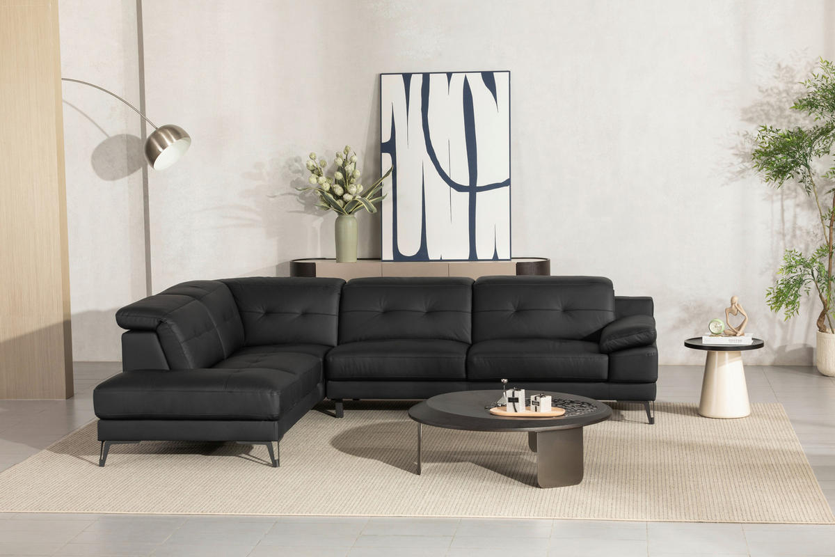 MID.YOU ECKSOFA Schwarz Echtleder, rechts davon: Webteppich, Couchtisch, Bild in blau, Topfpflanze in grün in hellem Wohnzimmer.