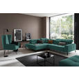Hom`in ECKSOFA Grün Feincord, links davon: Webteppich in schwarz, Polstersessel, rechts davon: Couchtisch in schwarz, Kissen in dunklem Wohnzimmer.