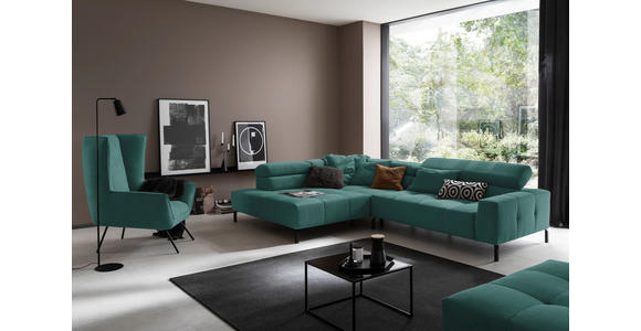 Hom`in ECKSOFA Grün Feincord, links davon: Webteppich in schwarz, Polstersessel, rechts davon: Couchtisch in schwarz, Kissen in dunklem Wohnzimmer.