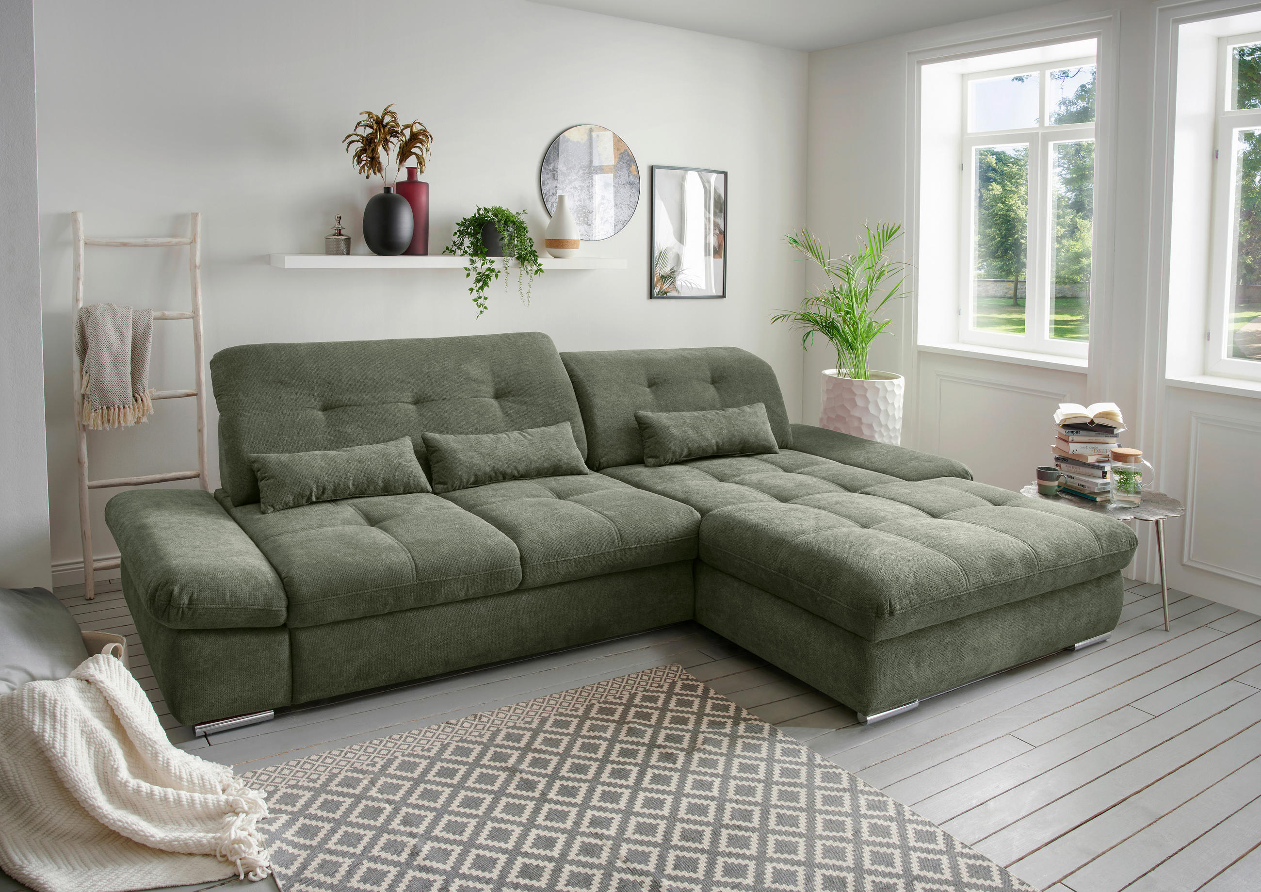 Livetastic ECKSOFA Dalida Dunkelgrün Chenille, links davon: Webteppich, Hängeregal in grün, Decke, rechts davon: Topfpflanze in hellem Wohnzimmer.