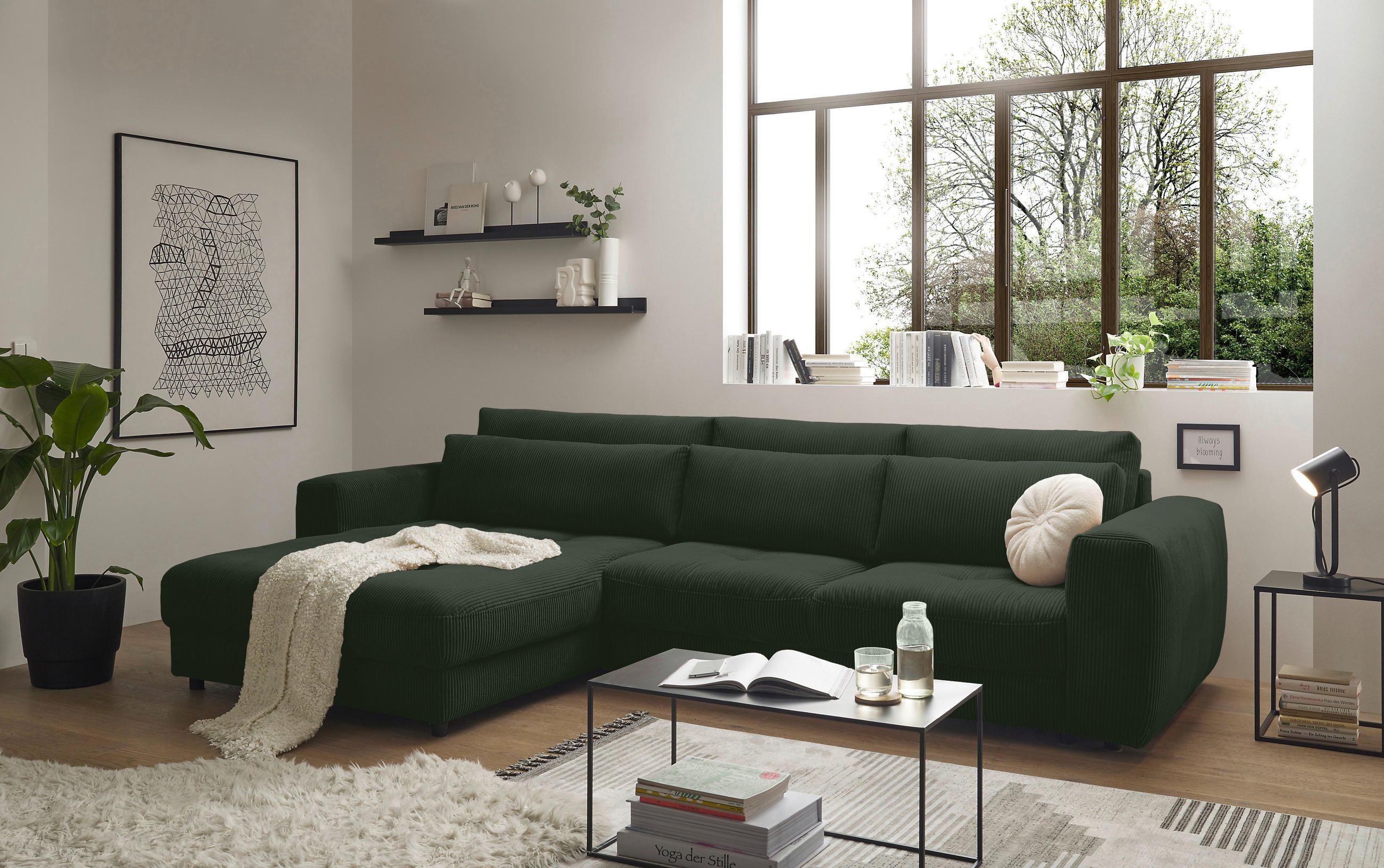 MID.YOU ECKSOFA Dunkelgrün Cord, links davon: Hochflorteppich, Decke, Hängeregal, rechts davon: Couchtisch in hellem Wohnzimmer.