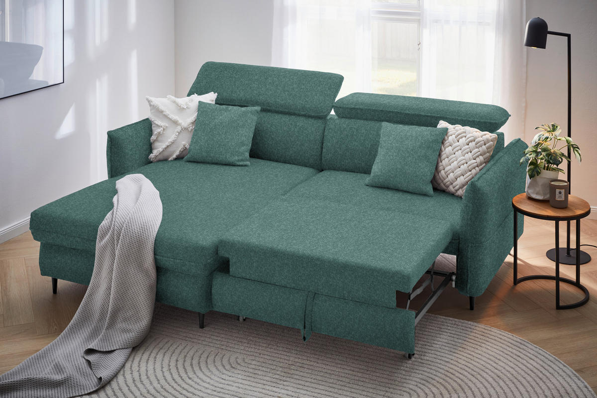 Stylife ECKSOFA Dunkelgrün Samt, rechts davon: Webteppich, Store, Beistelltisch, Kissen in hellem Wohnzimmer.