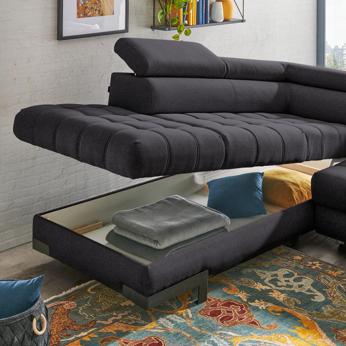 Welnova ECKSOFA Schwarz Webstoff, links davon: Hochflorteppich, Bild, rechts davon: Kissen in blau in dunklem Wohnzimmer.