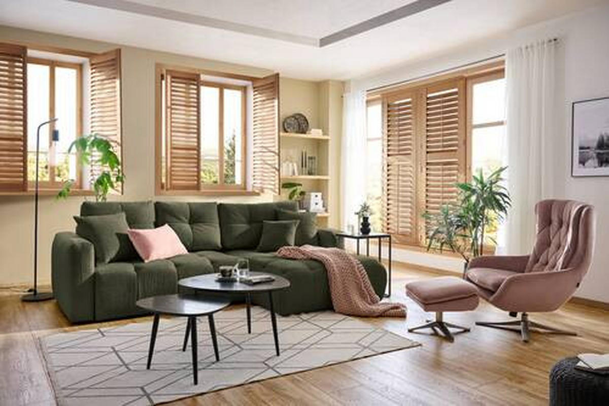 Hom`in ECKSOFA Dunkelgrün Chenille, links davon: Webteppich, rechts davon: Couchtisch, Decke in grün, Stuhl in hellem Wohnzimmer.