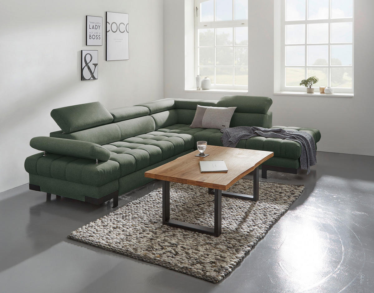 Welnova ECKSOFA Dunkelgrün Webstoff, rechts davon: Hochflorteppich in grau, Couchtisch, Kissen, Lektüre in weiß in hellem Wohnzimmer.