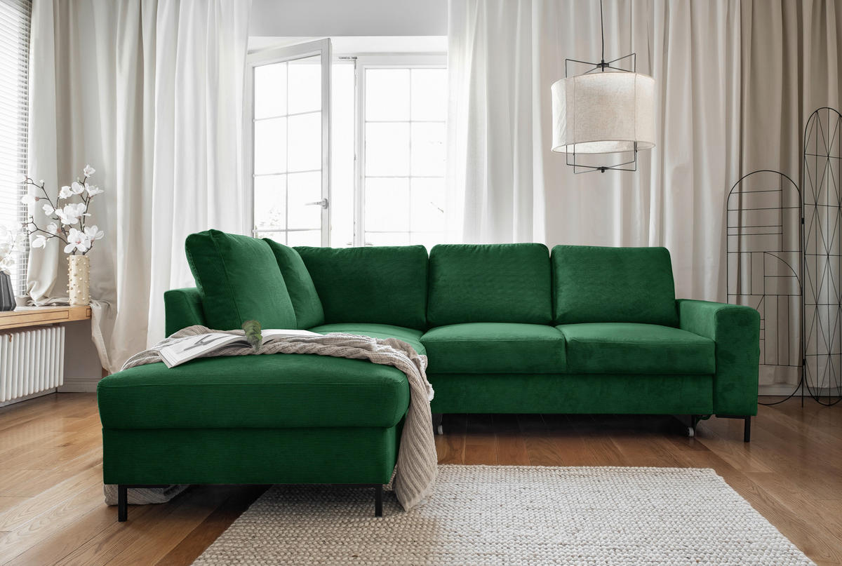 MID.YOU ECKSOFA Smaragdgrün Cord, links davon: Decke in grün, Vase, rechts davon: Hochflorteppich in weiß, Gardine in grün in hellem Wohnzimmer.