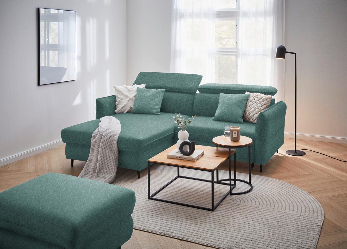 Stylife ECKSOFA Dunkelgrün Samt, links davon: Hocker in grün, rechts davon: Webteppich, Couchtisch in schwarz, Store in hellem Wohnzimmer.