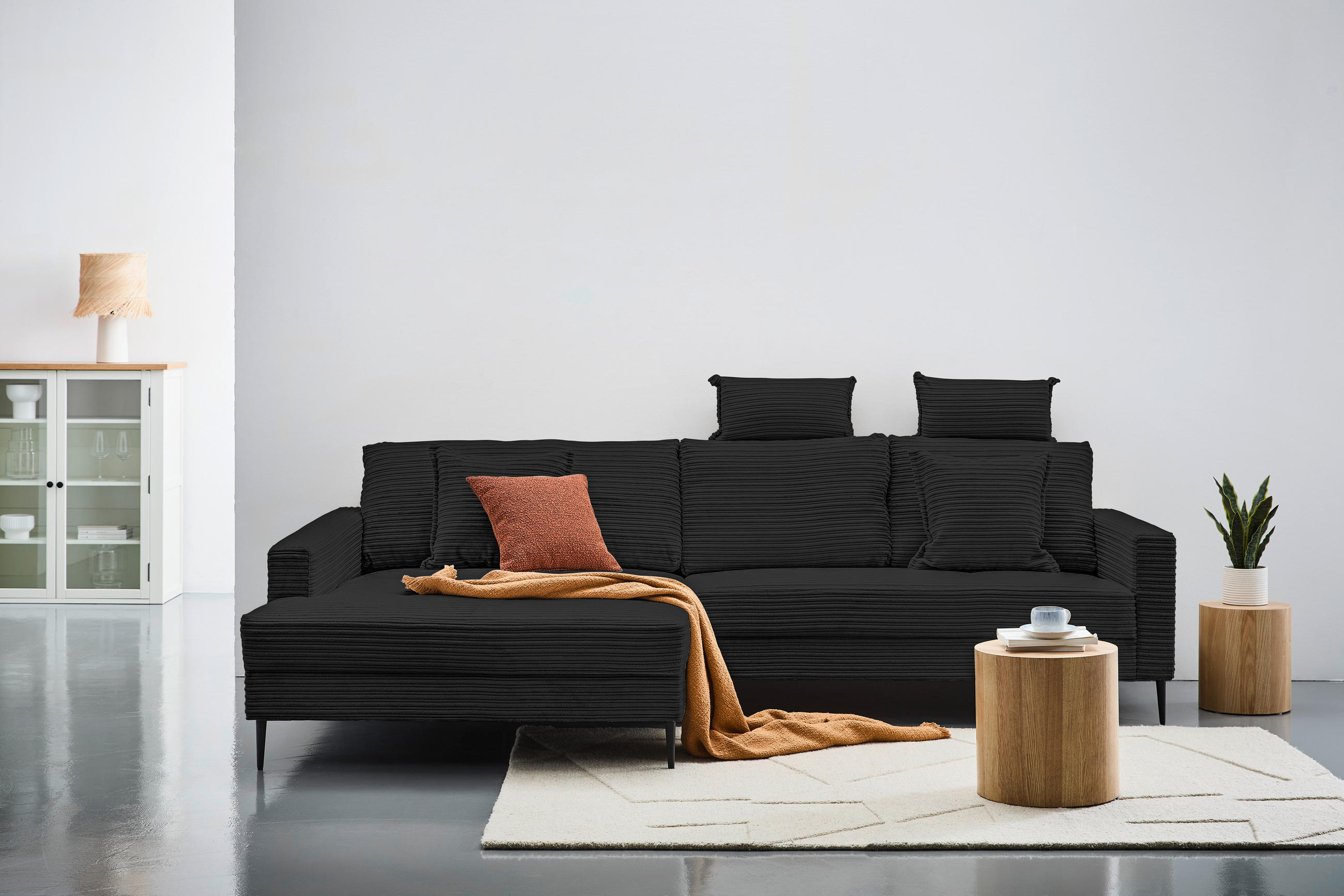 Carryhome Hochflorteppich, links davon: Sitzbank, Regal, Kissen in orange, rechts davon: Topfpflanze in grün in hellem Wohnzimmer.