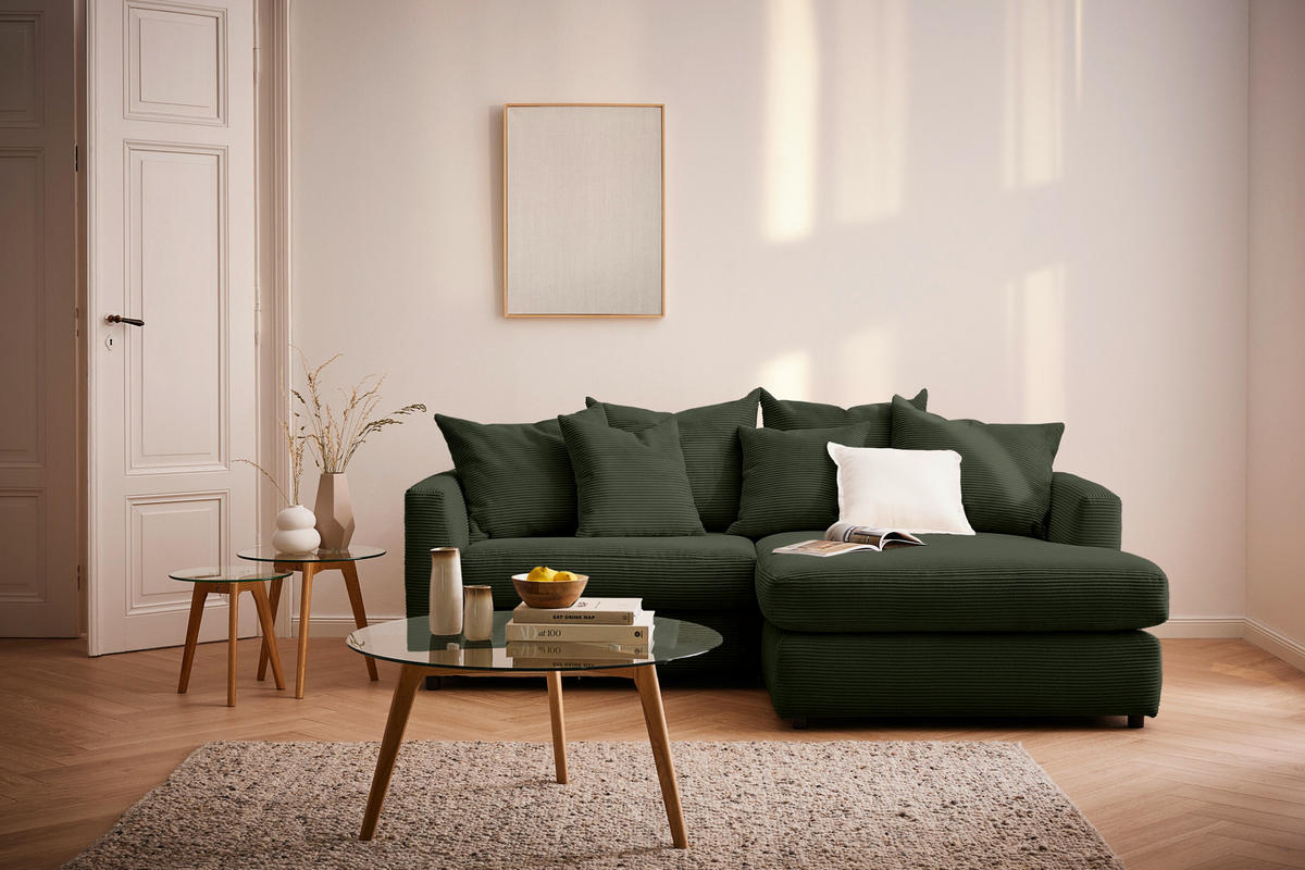 home24 ECKSOFA Dunkelgrün Cord, links davon: Hochflorteppich, Couchtisch, Beistelltisch in braun, Lektüre in hellem Wohnzimmer.