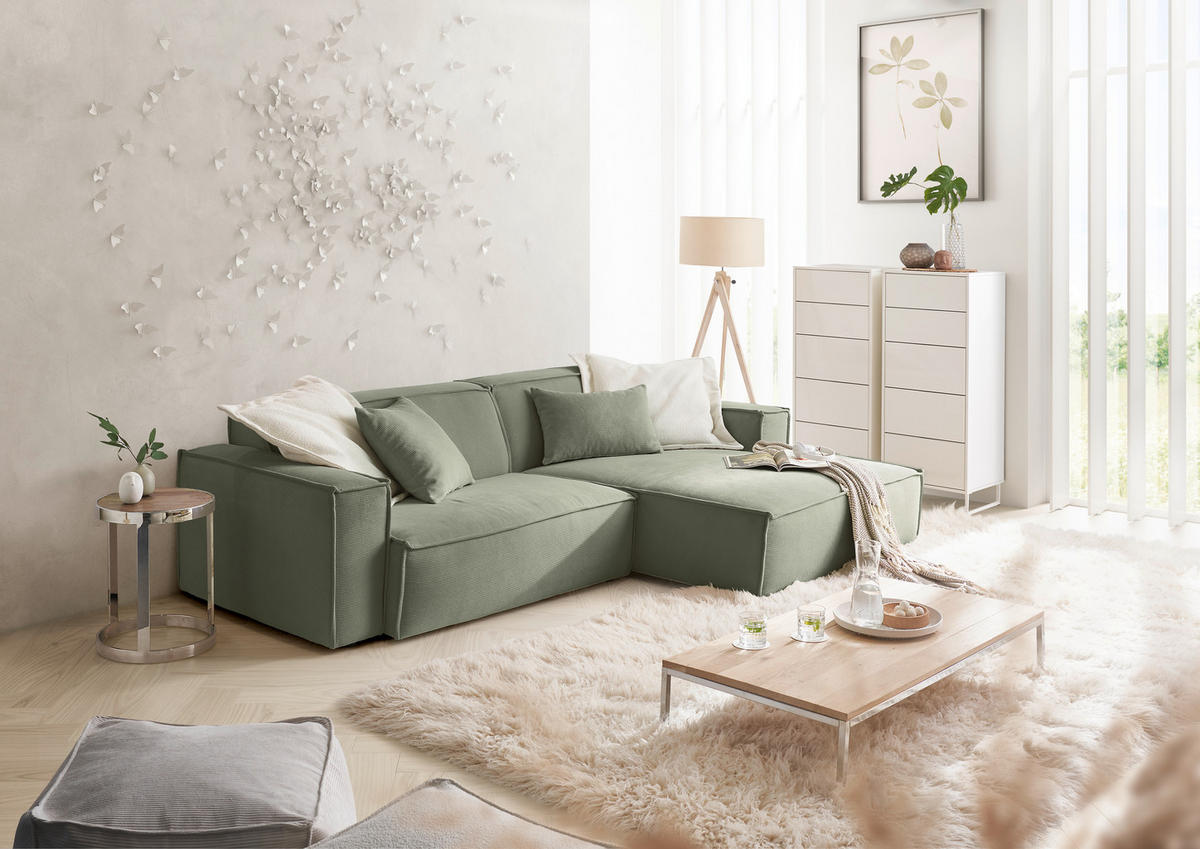Hom`in ECKSOFA Olivgrün Feincord, rechts davon: Kunstfell in weiß, Couchtisch in weiß, Highboard in weiß, Store in weiß in hellem Wohnzimmer.