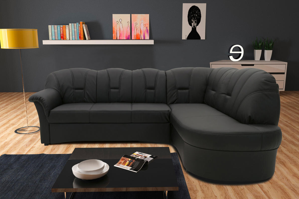 MID.YOU ECKSOFA Schwarz Lederlook, links davon: Couchtisch, Hängeregal, rechts davon: Nachttisch, Lektüre in schwarz in dunklem Wohnzimmer.