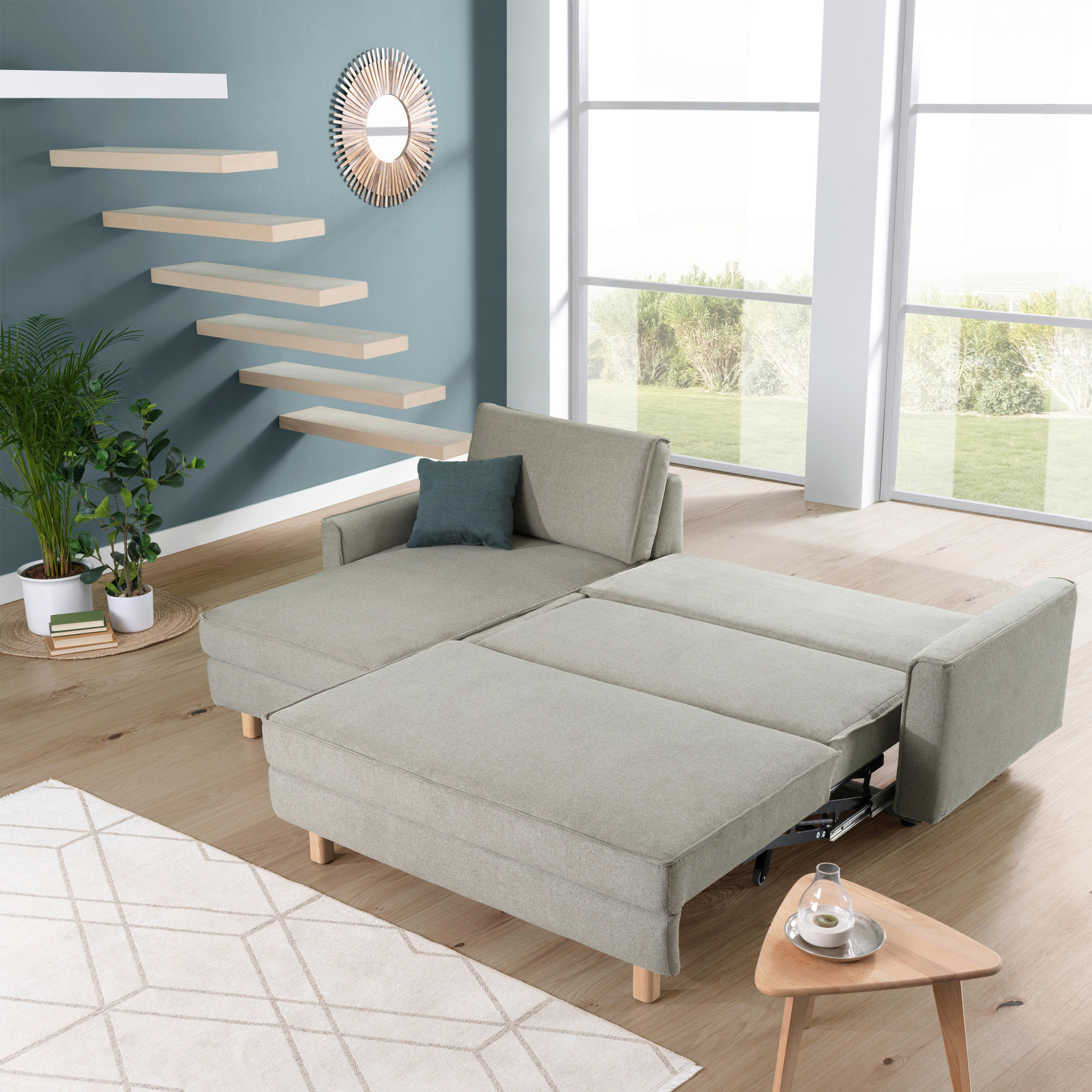 Sedda ECKSOFA Olivgrün Chenille, links davon: Hochflorteppich in weiß, Topfpflanze in grün, Deckenbeleuchtung, rechts davon: Couchtisch in hellem Wohnzimmer.
