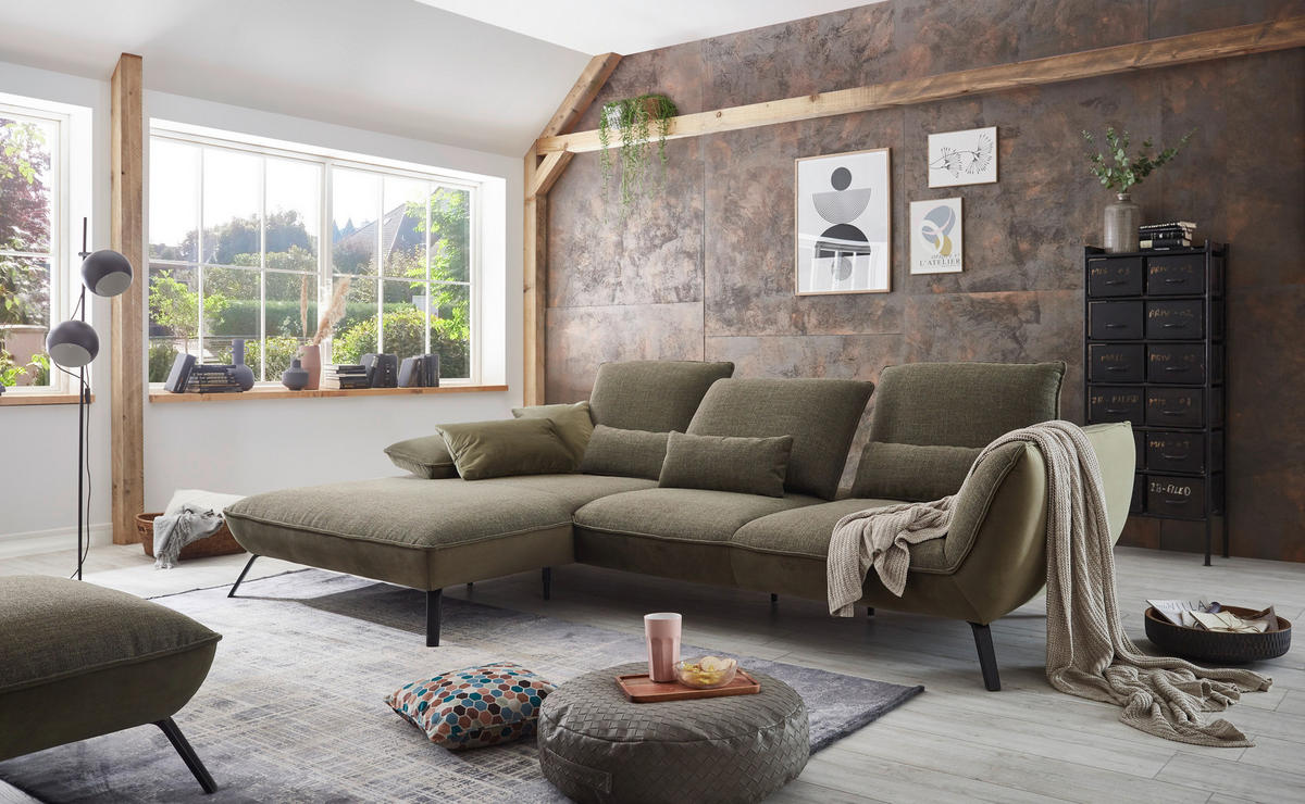 Moderano ECKSOFA Olivgrün Flachgewebe, links davon: Hochflorteppich, Kissen, rechts davon: Highboard, Lektüre in hellem Wohnzimmer.