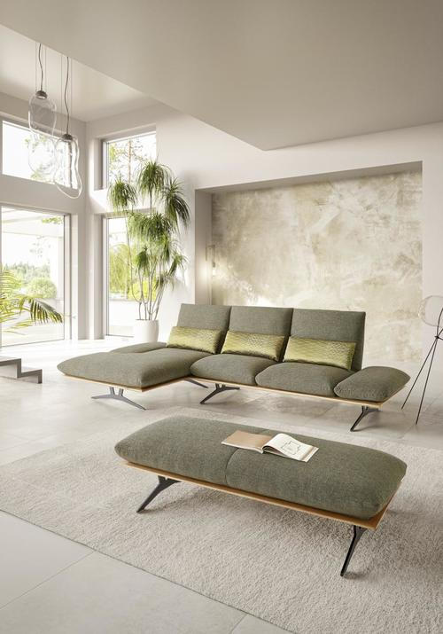 Dieter Knoll ECKSOFA Formia Grün Flachgewebe, links davon: Hochflorteppich in grün, Deckenbeleuchtung in weiß, rechts davon: Couchtisch in grün, Lektüre in weiß in hellem Esszimmer.