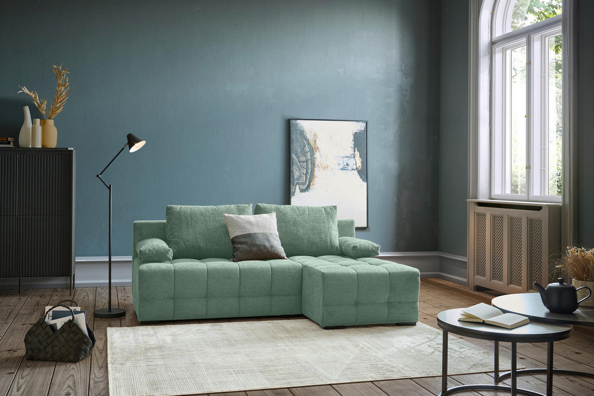 home24 ECKSOFA Dunkelgrün Chenille, links davon: Highboard, rechts davon: Hochflorteppich in weiß, Beistelltisch, Bild in blau in dunklem Wohnzimmer.