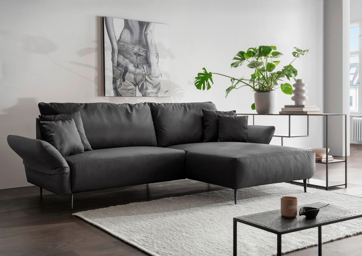 Livetastic ECKSOFA Schwarz Lederlook, links davon: Bild in grau, rechts davon: Hochflorteppich, Couchtisch, Topfpflanze in grün in hellem Wohnzimmer.