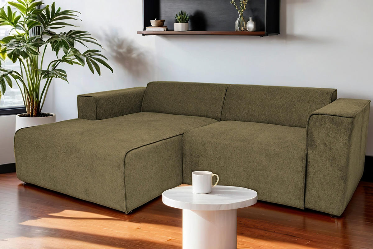 P & B ECKSOFA Olivgrün Struktur, links davon: Topfpflanze in grün, rechts davon: Beistelltisch in weiß in dunklem Wohnzimmer.
