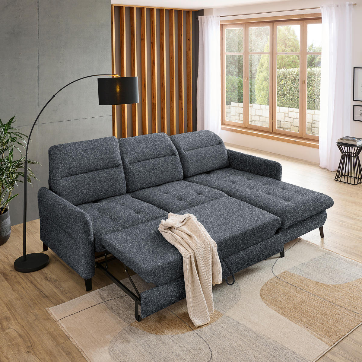 Livetastic ECKSOFA Schwarz Plüsch, links davon: Topfpflanze in grün, rechts davon: Hochflorteppich, Gardine, Store in weiß in hellem Wohnzimmer.