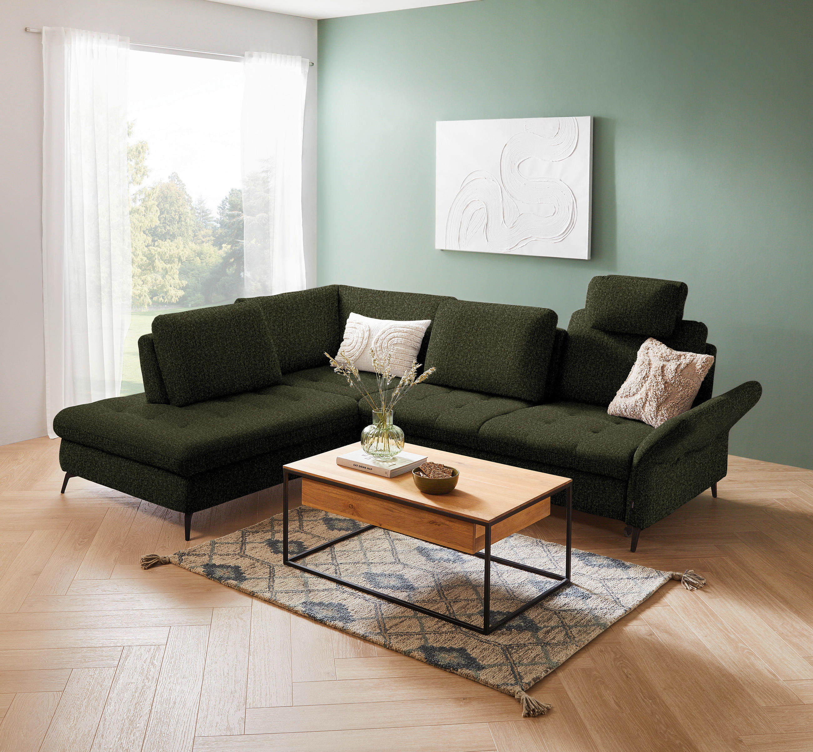 Valnatura ECKSOFA Olivgrün Struktur, links davon: Webteppich, rechts davon: Couchtisch, Bild in weiß, Kissen in hellem Wohnzimmer.
