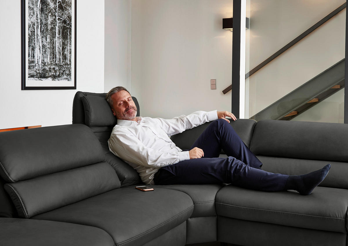 Hukla ECKSOFA Valdera Schwarz Echtleder, links davon: Bild in dunklem Wohnzimmer.