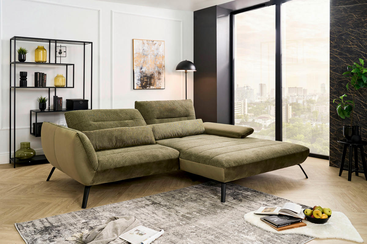 Carryhome ECKSOFA Olivgrün Webstoff, links davon: Webteppich, Regal, rechts davon: Lektüre in schwarz, Bild in hellem Wohnzimmer.