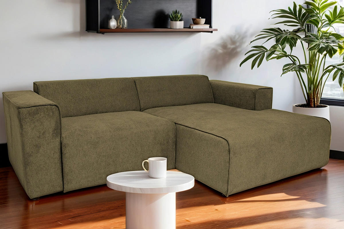 P & B ECKSOFA Olivgrün Struktur, rechts davon: Topfpflanze in grün, Beistelltisch in weiß in dunklem Wohnzimmer.