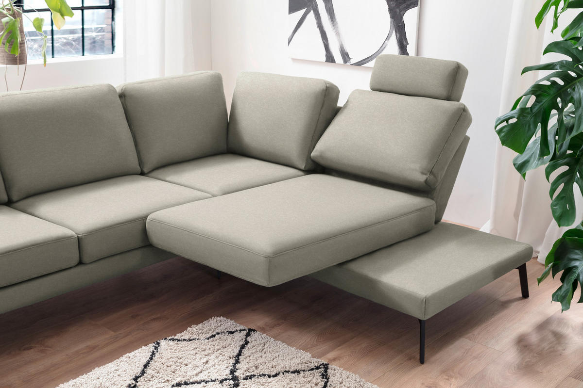 Hom`in ECKSOFA Olivgrün Mikrofaser, links davon: Hochflorteppich, rechts davon: Topfpflanze in grün in hellem Wohnzimmer.