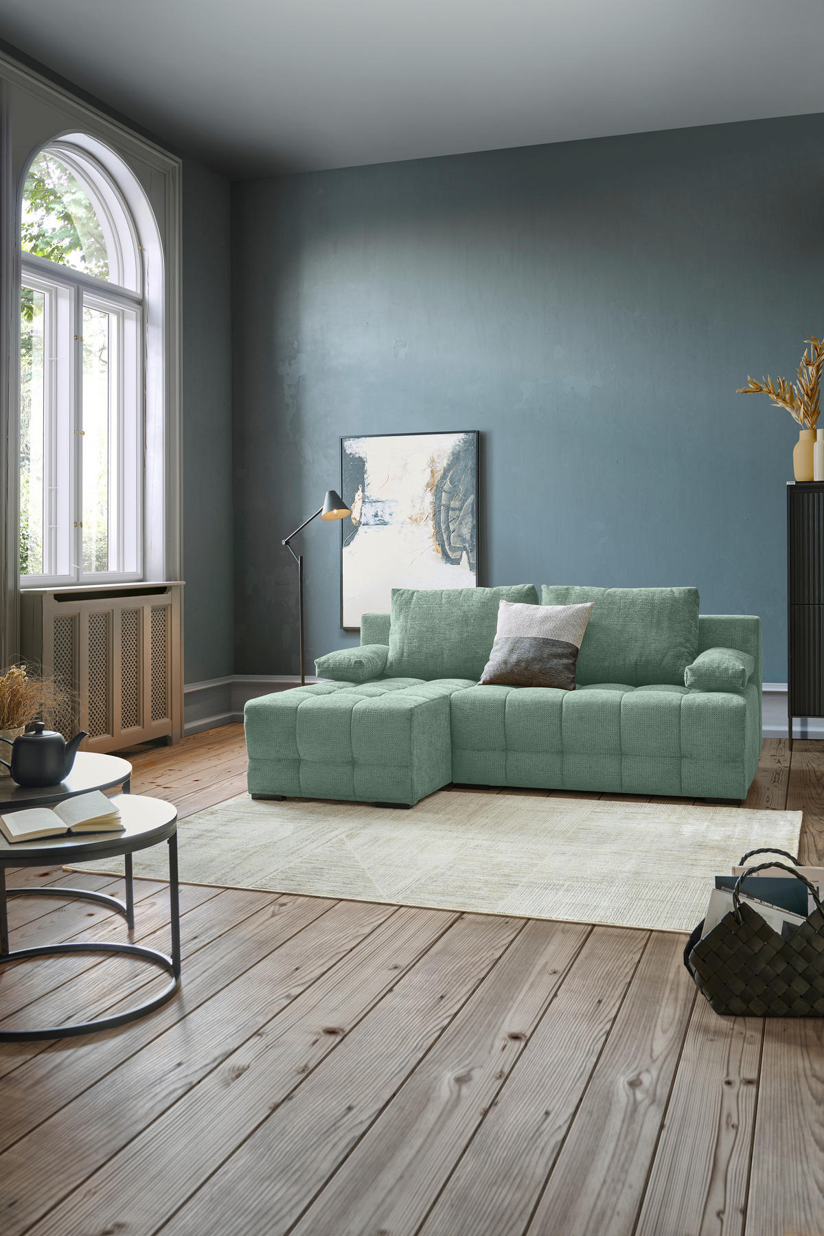 home24 ECKSOFA Dunkelgrün Chenille, links davon: Hochflorteppich in grün, Boxspringbett in grün, Beistelltisch, Highboard in hellem Wohnzimmer.