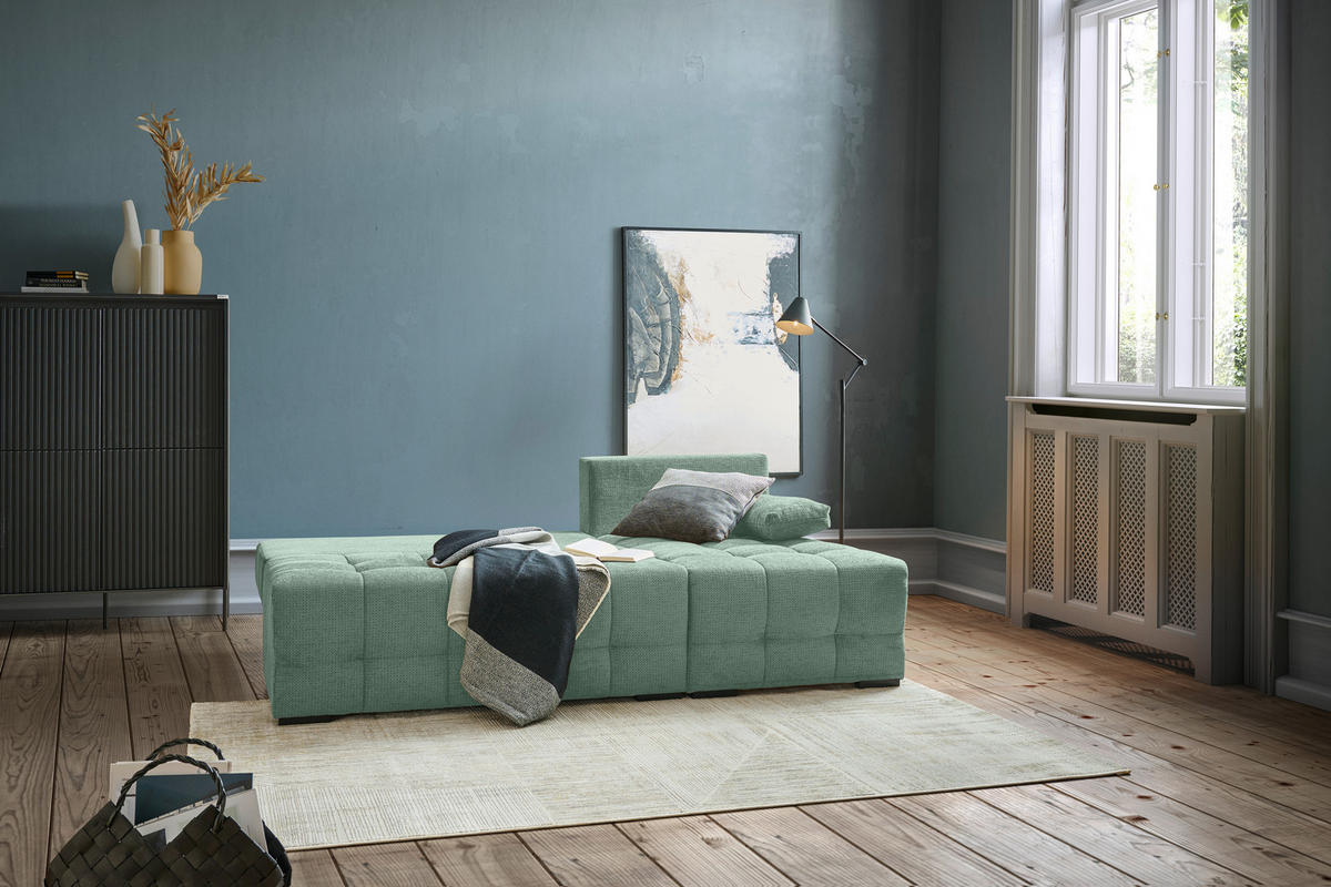 home24 ECKSOFA Dunkelgrün Chenille, links davon: Hochflorteppich in grün, Highboard, Vase, rechts davon: Bild in hellem Wohnzimmer.