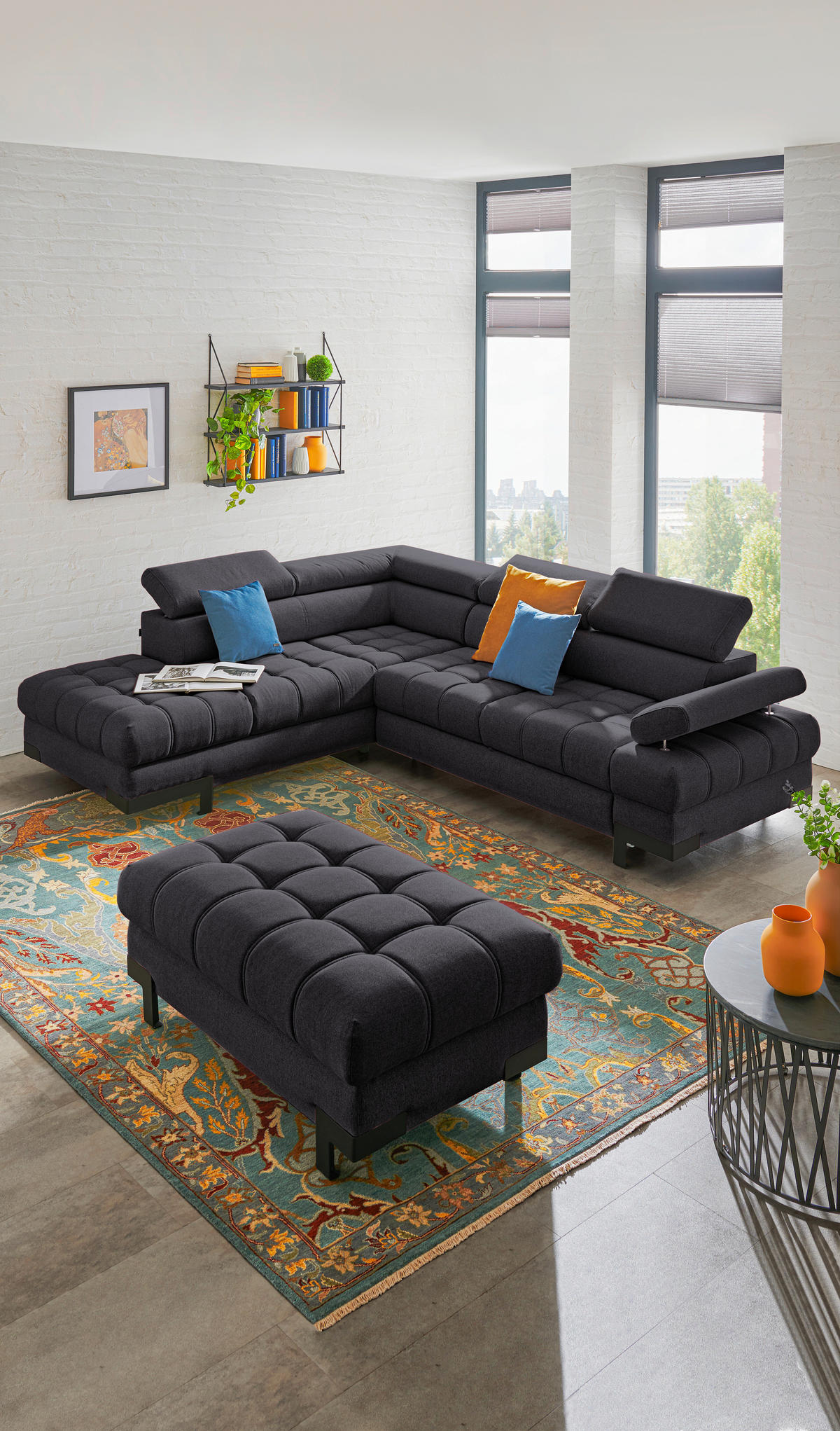 Welnova ECKSOFA Schwarz Webstoff, links davon: Webteppich, Bild in orange, Kissen in blau, Topfpflanze in hellem Wohnzimmer.