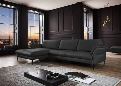 Hukla ECKSOFA Schwarz Echtleder, links davon: Hochflorteppich, Couchtisch in schwarz, rechts davon: Lektüre in dunklem Wohnzimmer.