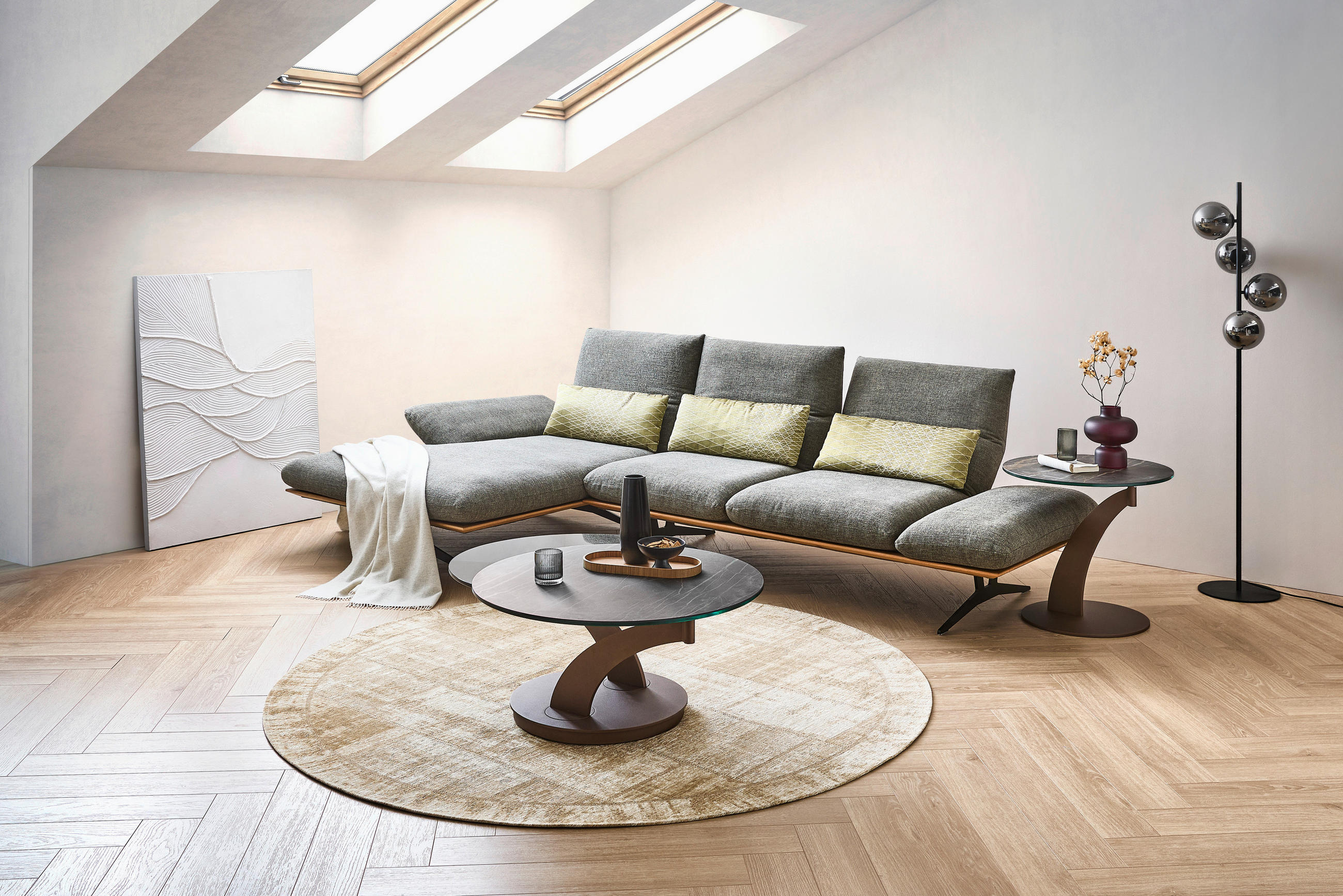 Dieter Knoll ECKSOFA Formia Grün Flachgewebe, links davon: Hochflorteppich, Decke in weiß, rechts davon: Couchtisch in braun, Kissen in gelb in hellem Wohnzimmer.