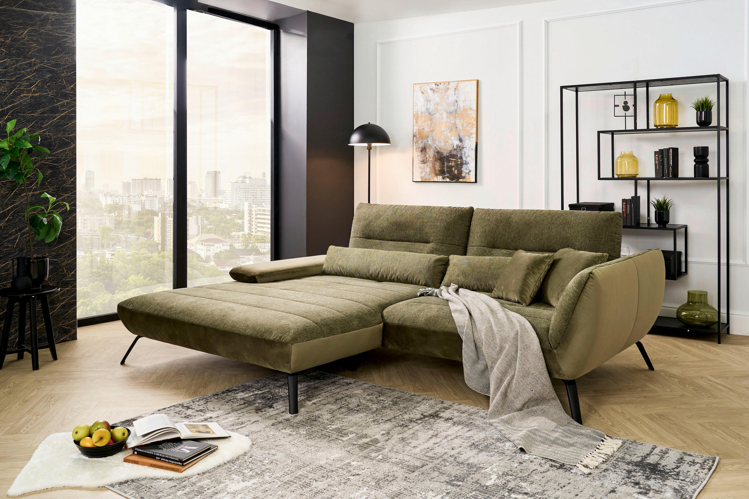 Carryhome ECKSOFA Olivgrün Webstoff, links davon: Webteppich, Lektüre in schwarz, rechts davon: Decke, Regal in hellem Wohnzimmer.