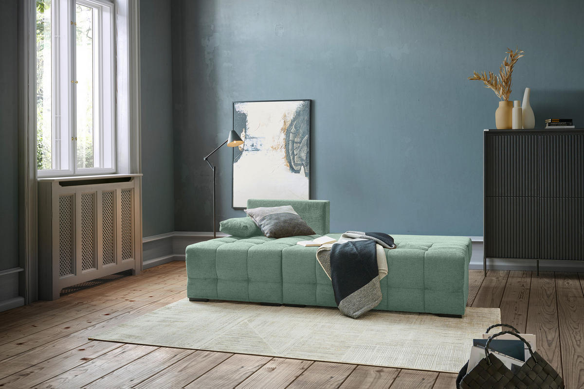home24 ECKSOFA Dunkelgrün Chenille, rechts davon: Hochflorteppich in grün, Highboard, Bild in blau, Vase in weiß in hellem Schlafzimmer.