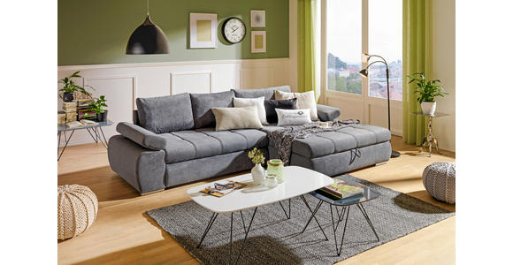 Das Bild zeigt ein Wohnzimmer mit einer grauen Couch, einem Couchtisch, einem Beistelltisch, einem Hocker, einem Teppich, einer Stehlampe, einem Vorhang, einem Fenster, einer Uhr, drei Bildern und zwei Pflanzen.