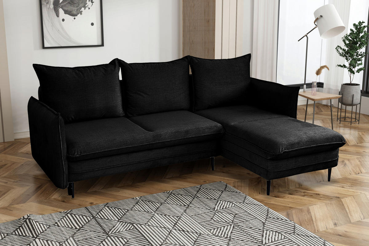MID.YOU ECKSOFA Schwarz Flachgewebe, links davon: Bild in weiß, rechts davon: Webteppich, Gardine, Topfpflanze in dunklem Wohnzimmer.