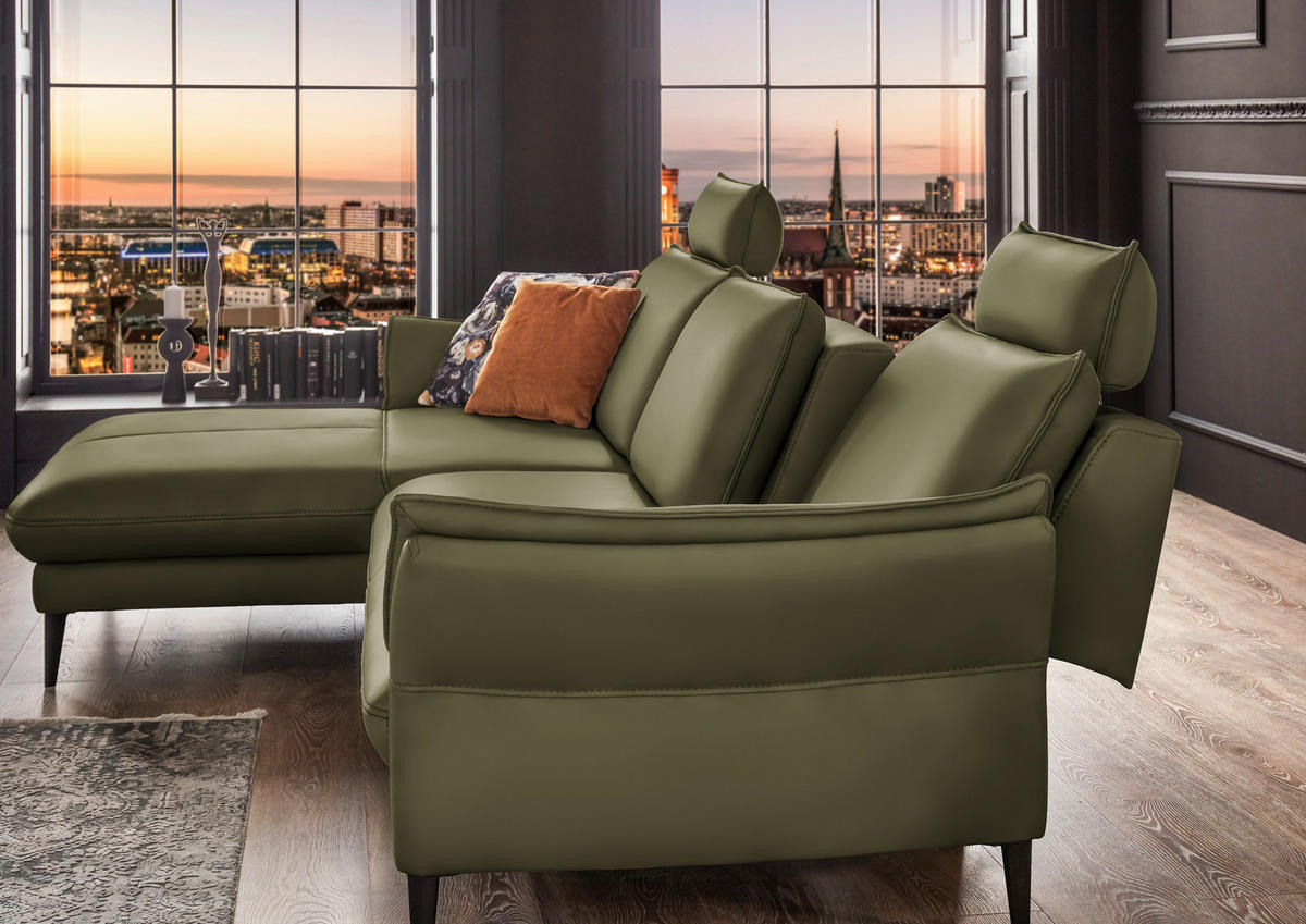 Hukla ECKSOFA Grün Echtleder, rechts davon: Kissen in orange, Deckenbeleuchtung in grün in dunklem Wohnzimmer.